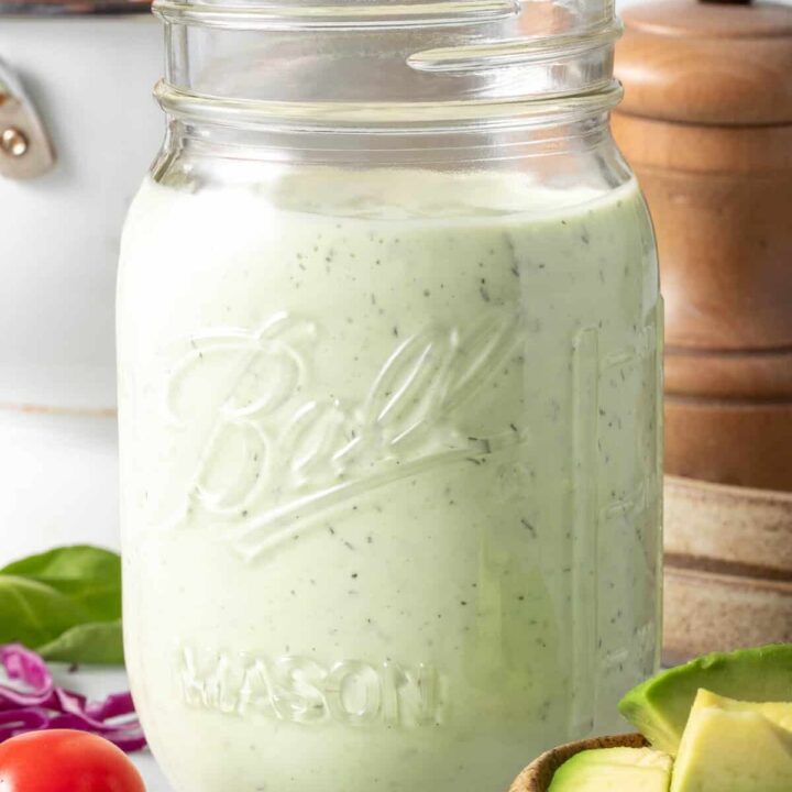 A clear mason jar filled with Avocado Ranch Dressing.