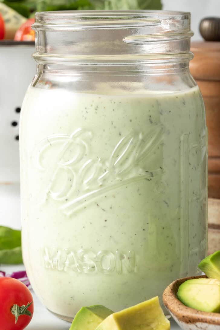 A clear mason jar filled with Avocado Ranch Salad Dressing.