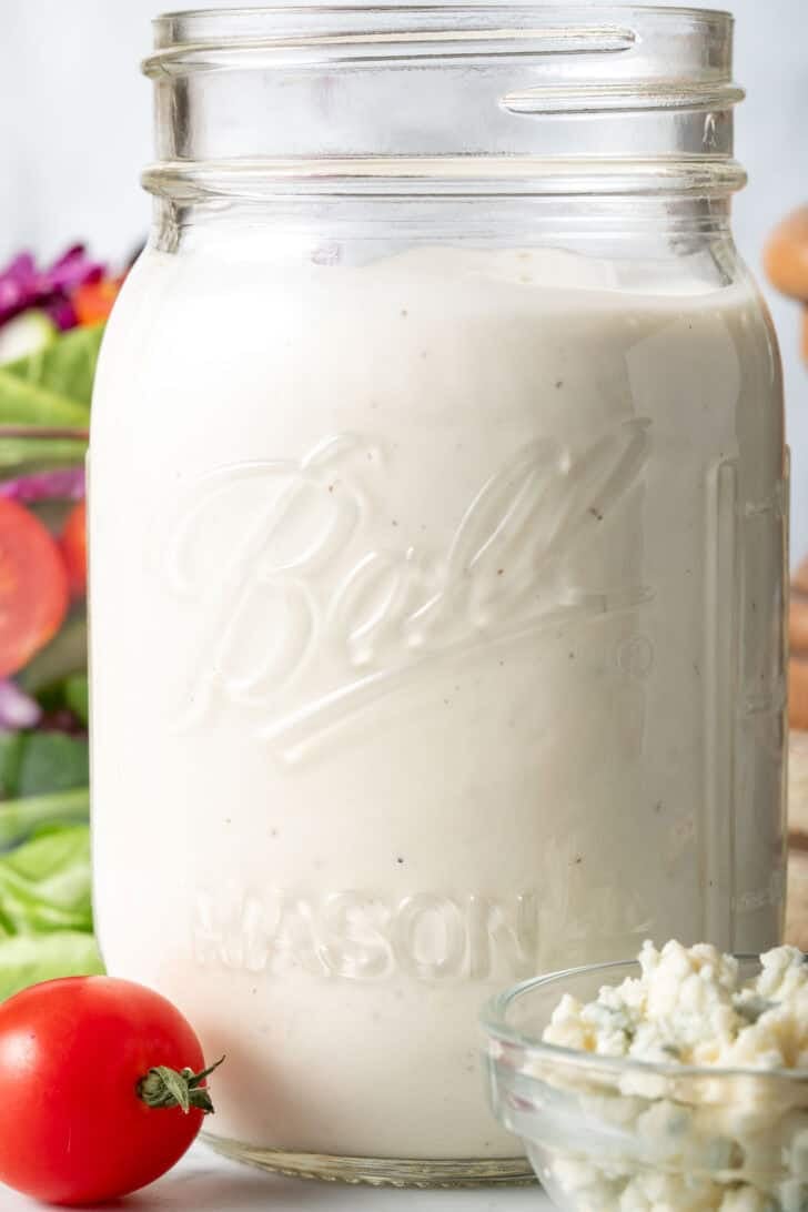 A clear mason jar filled with the Best Blue Cheese Dressing.