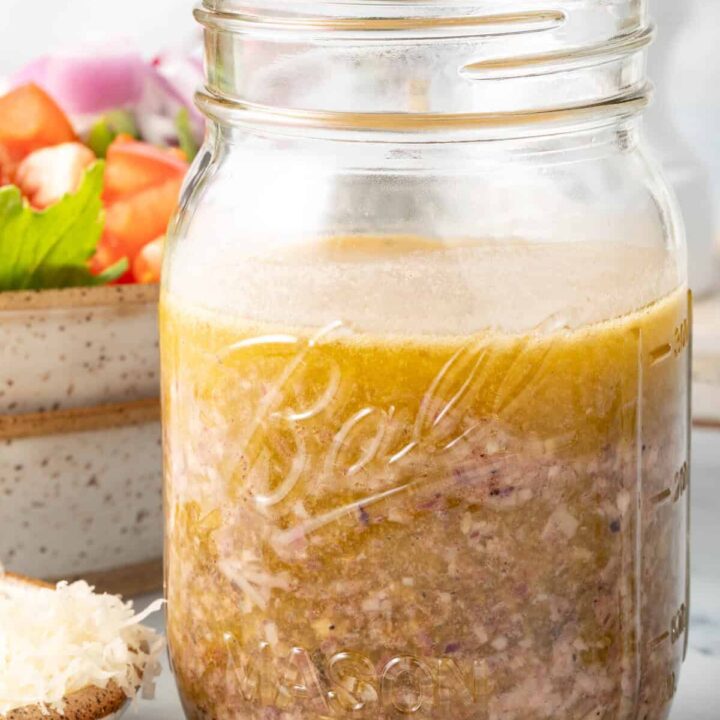 A clear mason jar filled with Greek Vinaigrette.