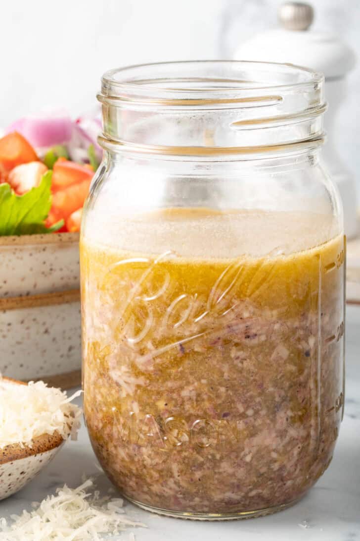 A clear mason jar filled with Greek Vinaigrette.