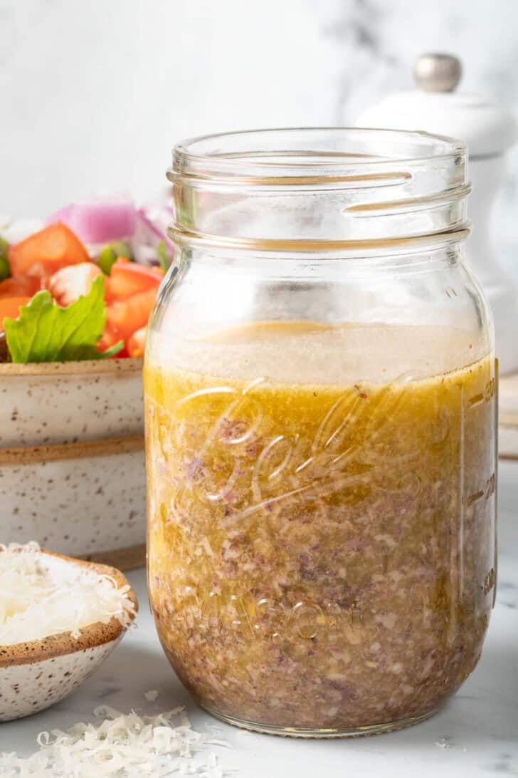 A clear mason jar filled with the best Greek salad dressing.