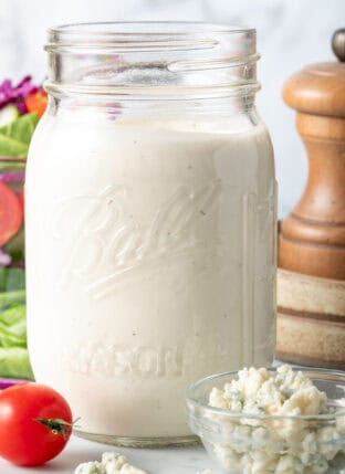 A clear glass mason jar filled with homemade Blue Cheese Dressing