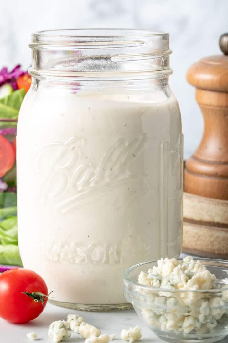 A clear mason jar filled with homemade blue cheese dressing.