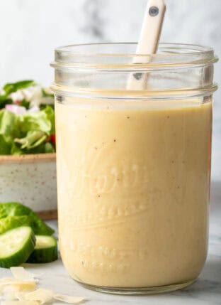 A clear glass mason jar filled with Dijon Mustard Vinaigrette.