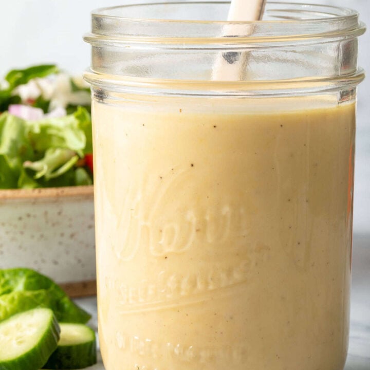 A clear glass mason jar filled with Dijon Mustard Vinaigrette.