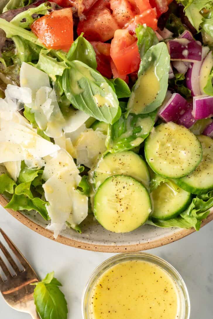 A bowl filled with salad tossed with Lemon Vinaigrette Salad Dressing.
