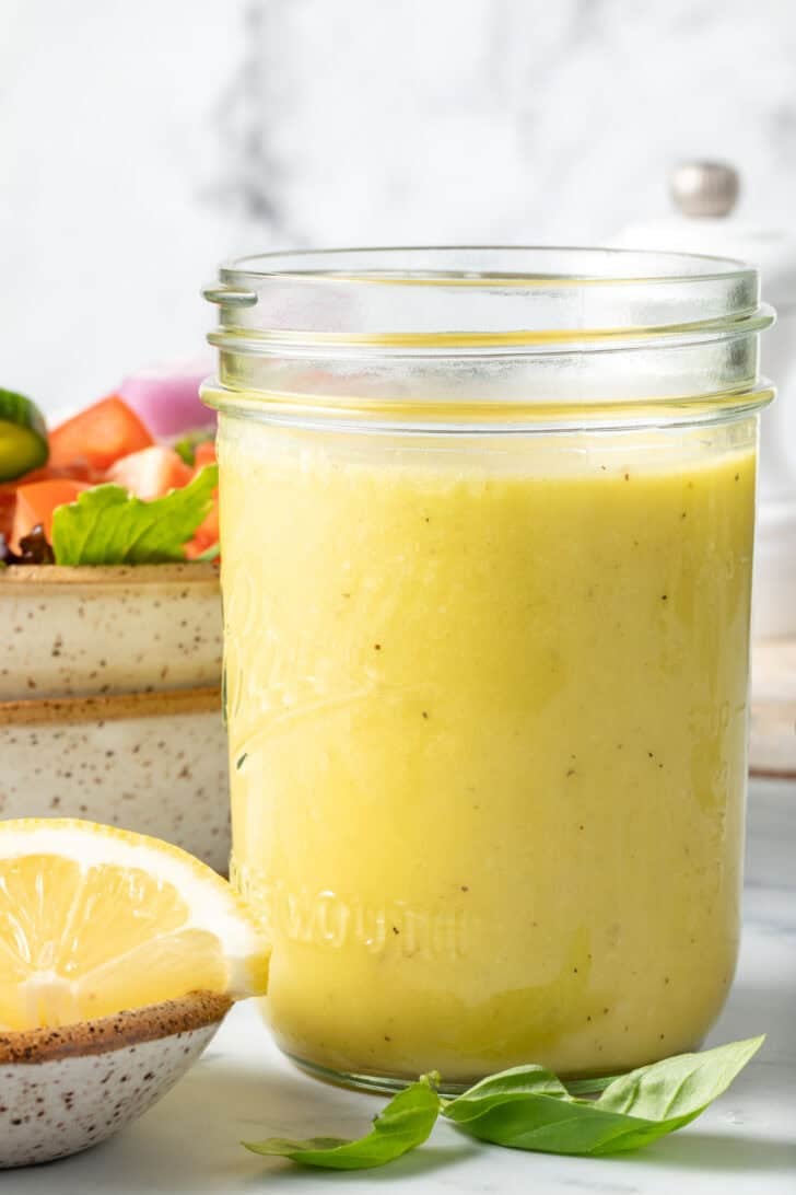 A clear glass mason jar filled with the best Lemon Vinaigrette.