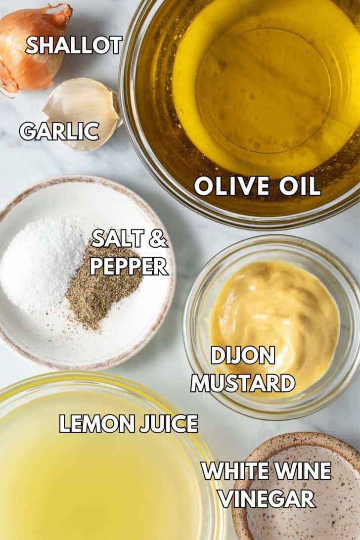 Small clear bowls filled with olive oil, Dijon mustard, white wine vinegar and lemon juice.