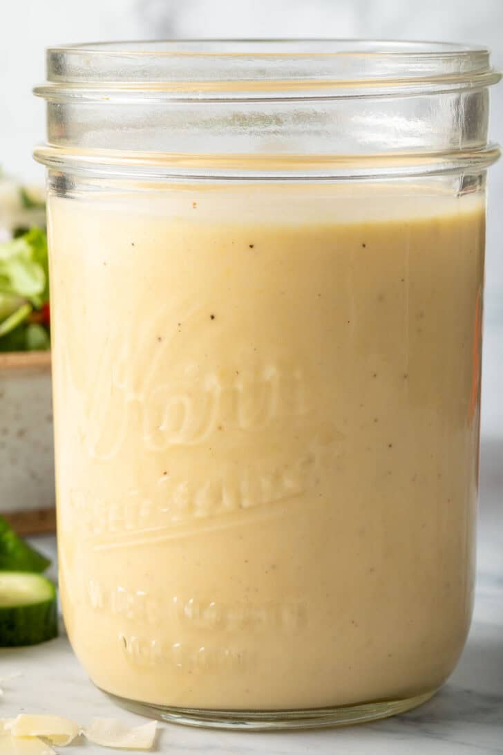 A clear mason jar filled with Dijon Mustard Salad Dressing.