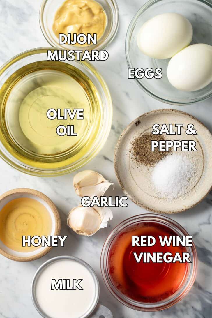 Glass bowls filled with olive oil, red wine vinegar, honey, milk and eggs for a homemade dressing.