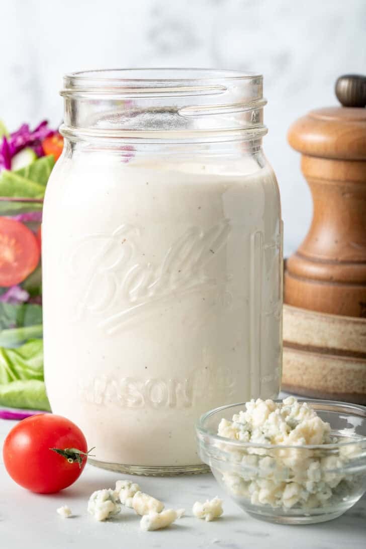A clear mason jar filled with Homemade Blue Cheese Salad Dressing.