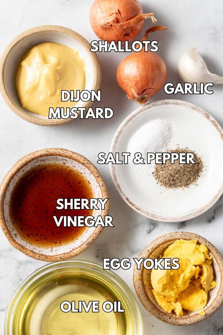 Small bowls filled with vinegar, mustard, hardboiled egg yolks and olive oil.