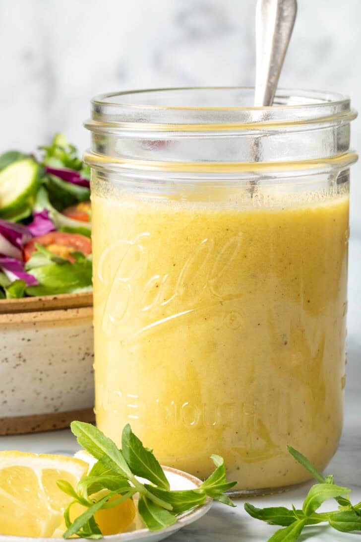 A clear glass mason jar filled with Tarragon Vinaigrette.