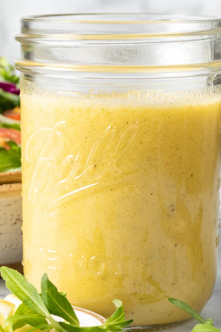 A clear mason jar filled with Lemon Tarragon Salad Dressing.