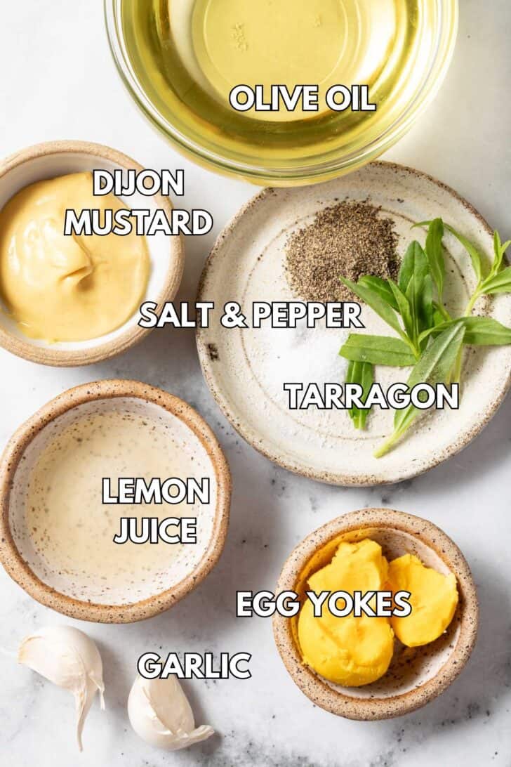 Small bowls filled with olive oil, lemon juice, Dijon mustard, egg yolks and fresh herbs for a salad dressing.