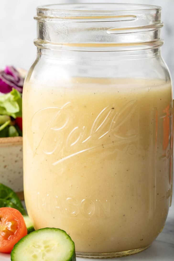 A clear mason jar filled with White Balsamic Salad Dressing.