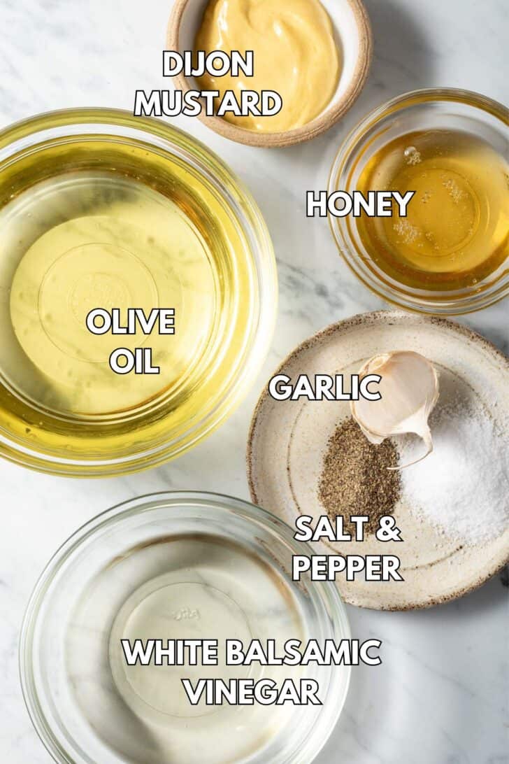 Glass bowls filled with olive oil, honey, Dijon mustard and white vinegar.