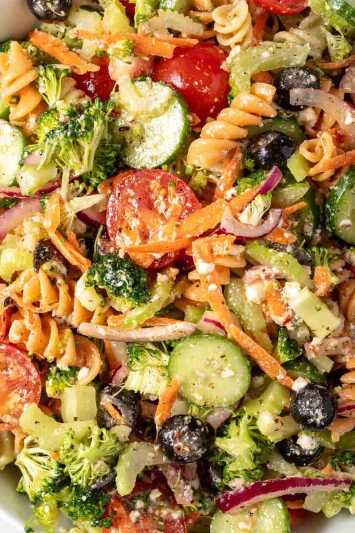A white bowl filled with the best Summer Pasta Salad (crispy vegetables and noodles tossed in a delicious creamy vinaigrette).