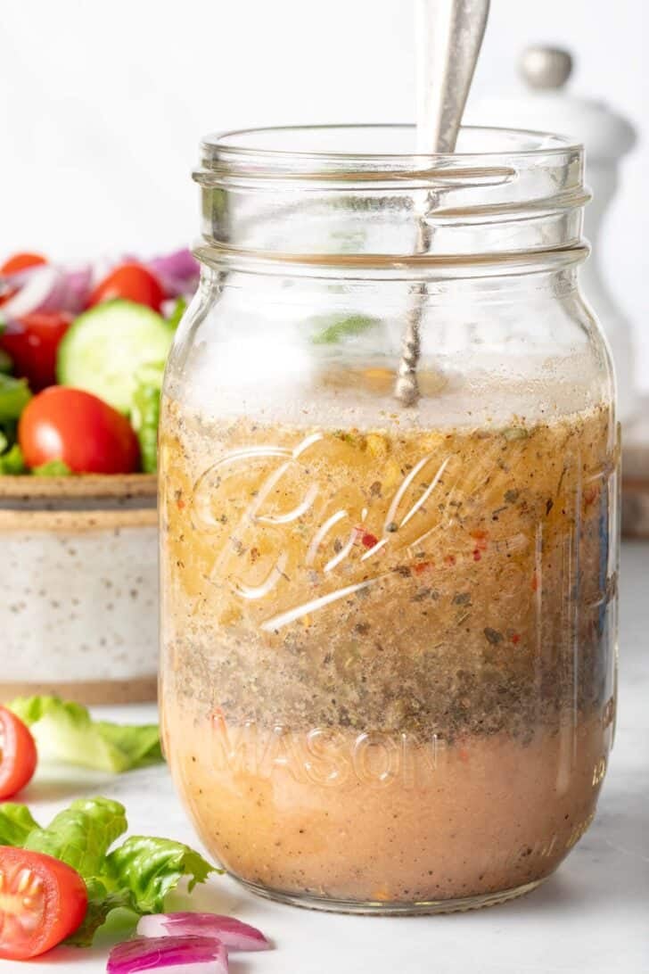 A clear mason jar filled with Zesty Italian Salad Dressing.