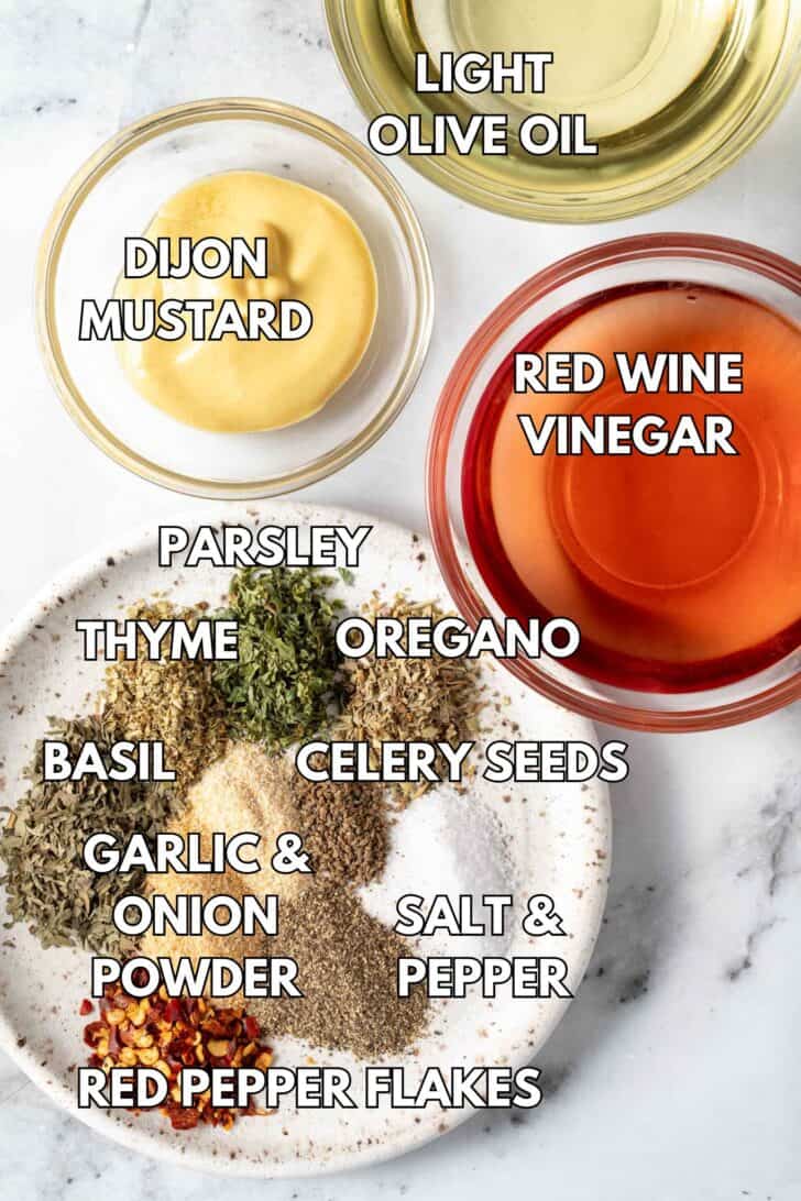 Clear glass bowls filled with red wine vinegar, Dijon mustard, light olive oil and a small plate filled with dried seasonings.