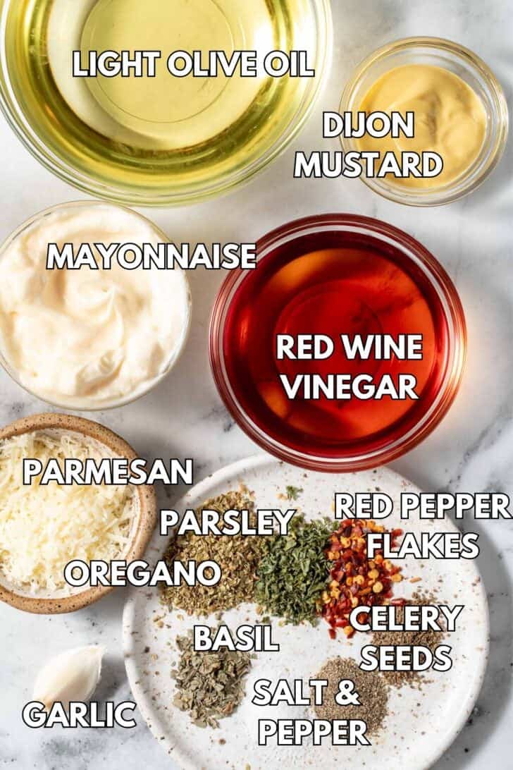 Clear glass bowls filled with mayonnaise, olive oil, red wine vinegar, Dijon mustard, Parmesan cheese and seasoning.