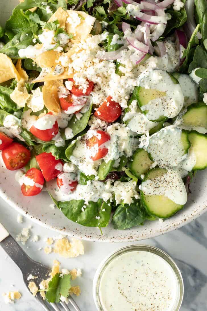 A white bowl filled with salad tossed with Mexican Caesar Salad Dressing.