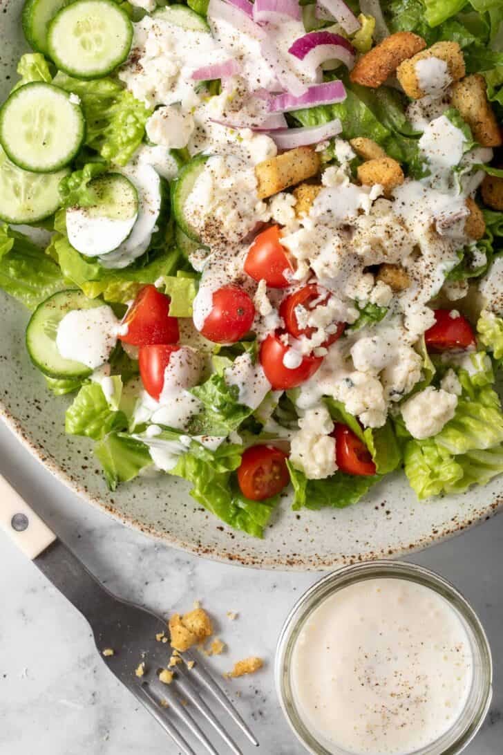 A chopped salad on a plate tossed with homemade buttermilk salad dressing.