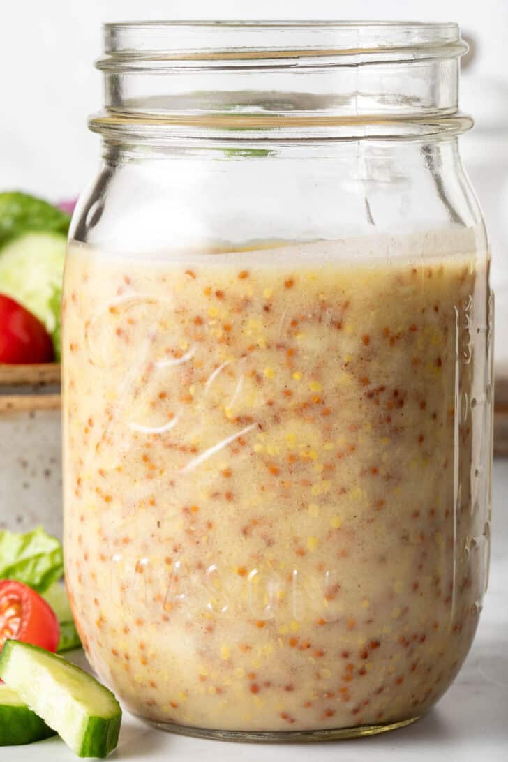 A clear mason jar filled with Homemade Honey Mustard Dressing.