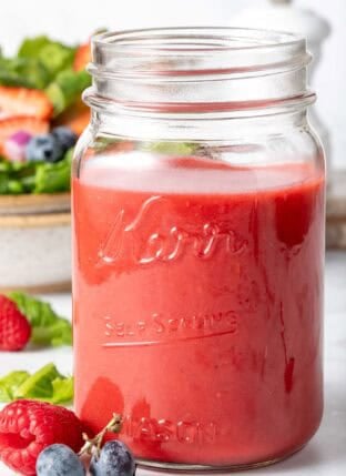 A clear mason jar filled with homemade Raspberry Vinaigrette.