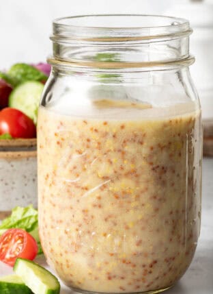 A clear mason jar filled with Honey Mustard Dressing