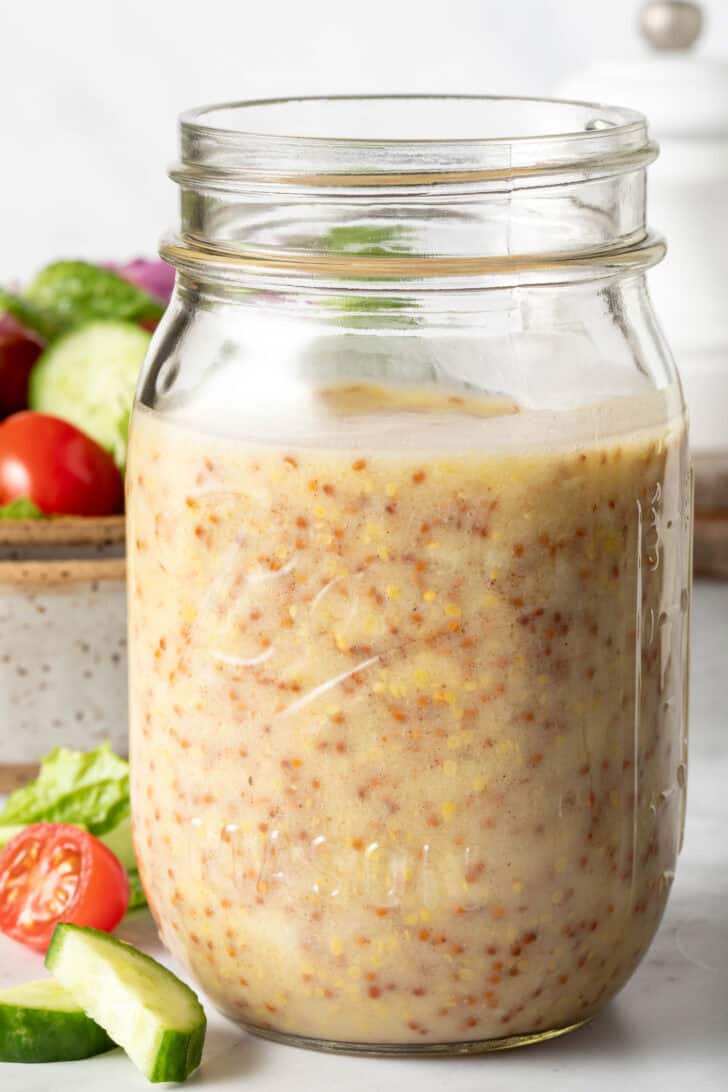 A clear mason jar filled with Honey Mustard Dressing.