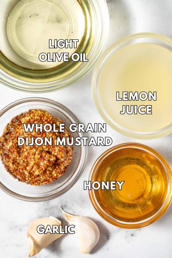 Small clear bowls filled with lemon juice, light olive oil, whole grain Dijon mustard and honey.