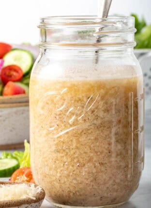 A clear glass mason jar filled with Creamy Italian Dressing.