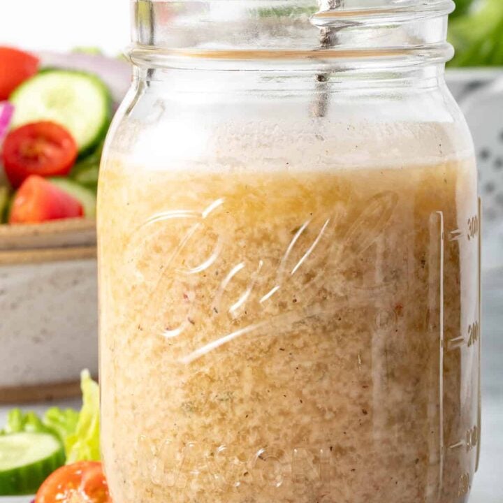 A clear glass mason jar filled with Creamy Italian Dressing.