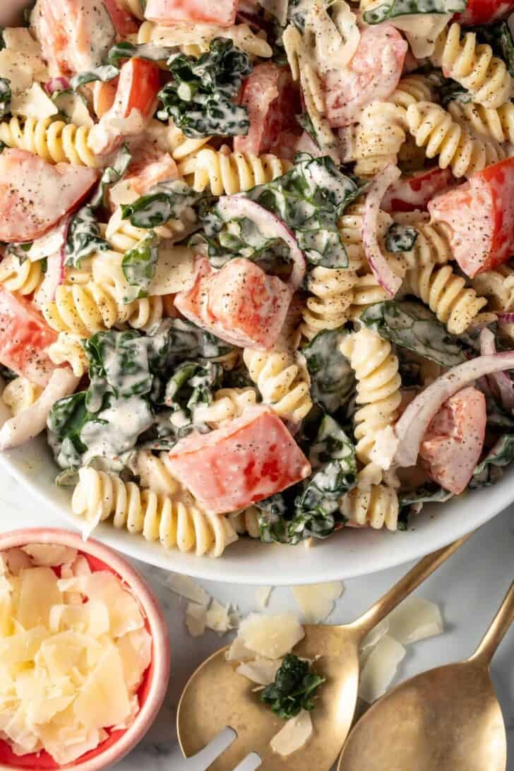 A white bowl filled with Kale Pasta Salad.