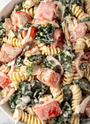 A white bowl filled with Kale Pasta Salad.