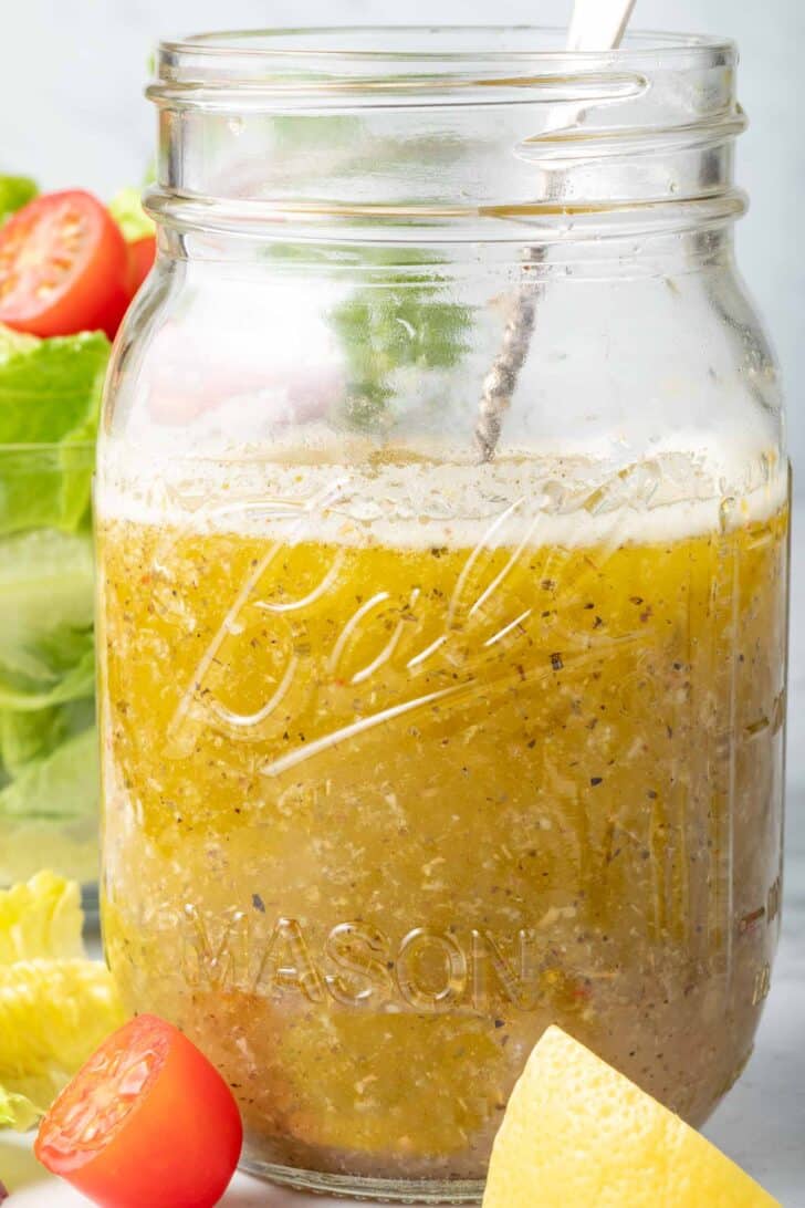 A clear mason jar filled with the best Mediterranean Salad Dressing.