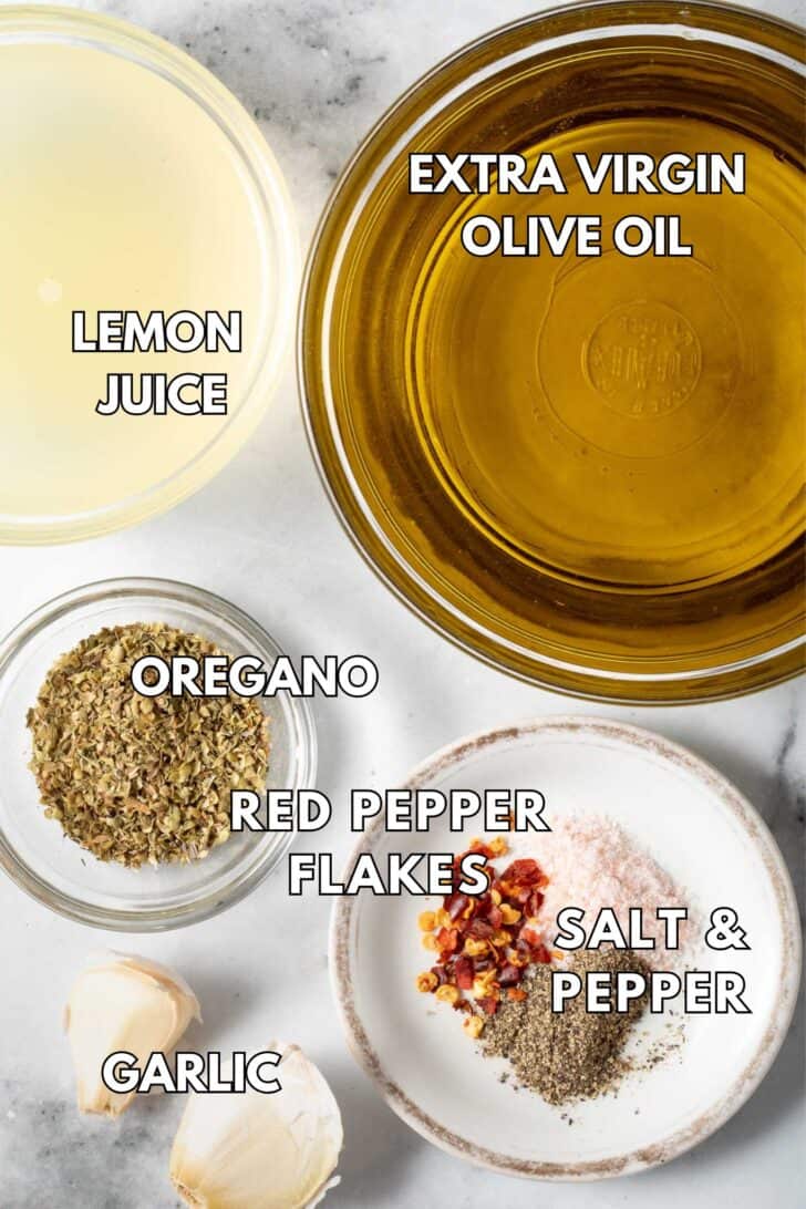 Small clear bowls filled with lemon juice, olive oil, dried oregano and garlic, salt and pepper.