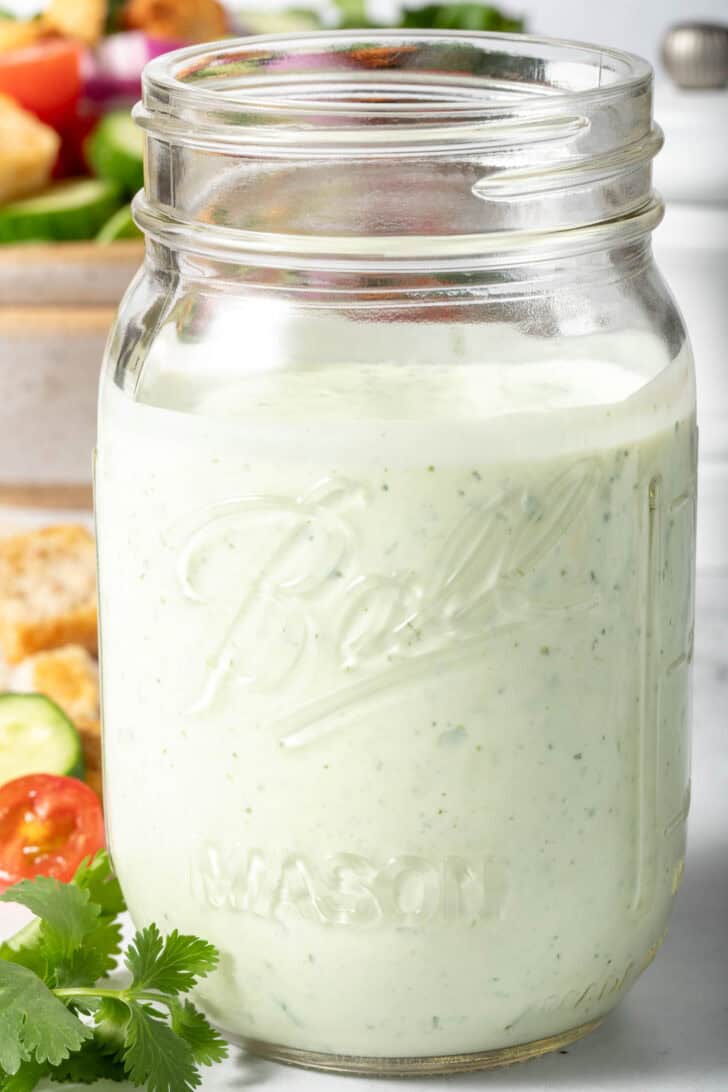 A clear mason jar filled with Mexican Caesar Salad Dressing.