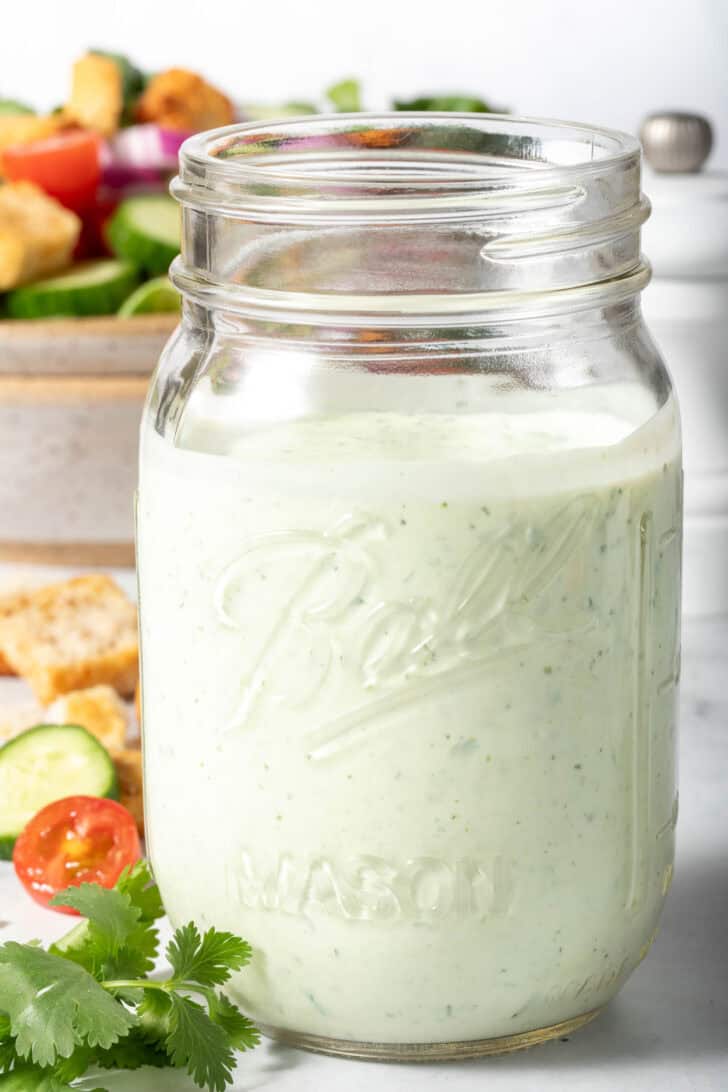 A clear mason jar filled with Mexican Caesar Salad Dressing.