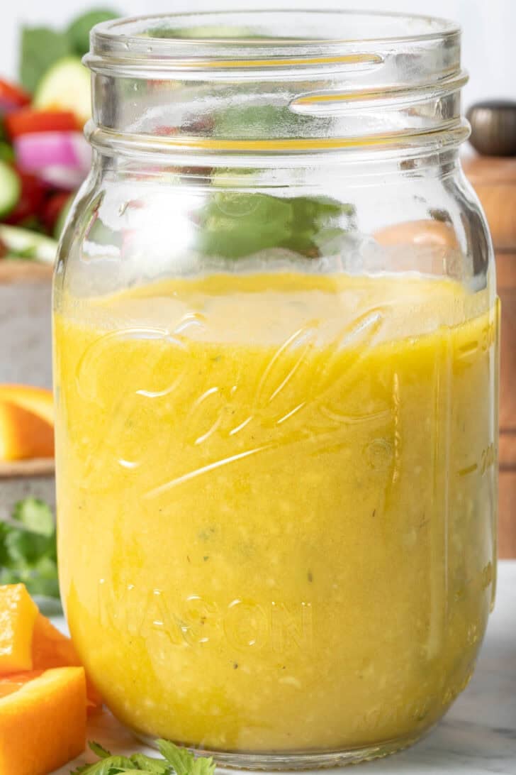 A clear mason jar filled with Orange Vinaigrette dressing.