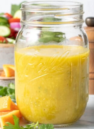 A clear mason jar filled with Orange Vinaigrette Dressing.