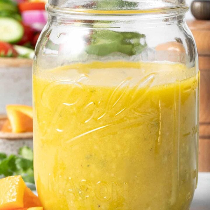 A clear mason jar filled with Orange Vinaigrette Dressing.
