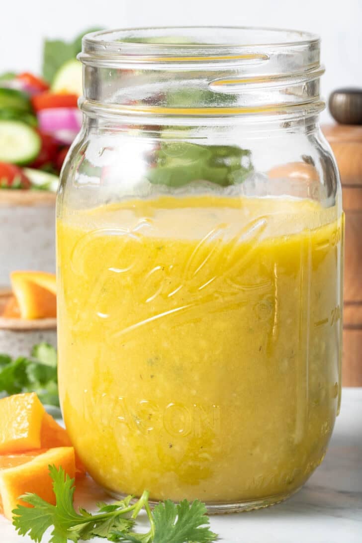A clear mason jar filled with Orange Vinaigrette dressing.