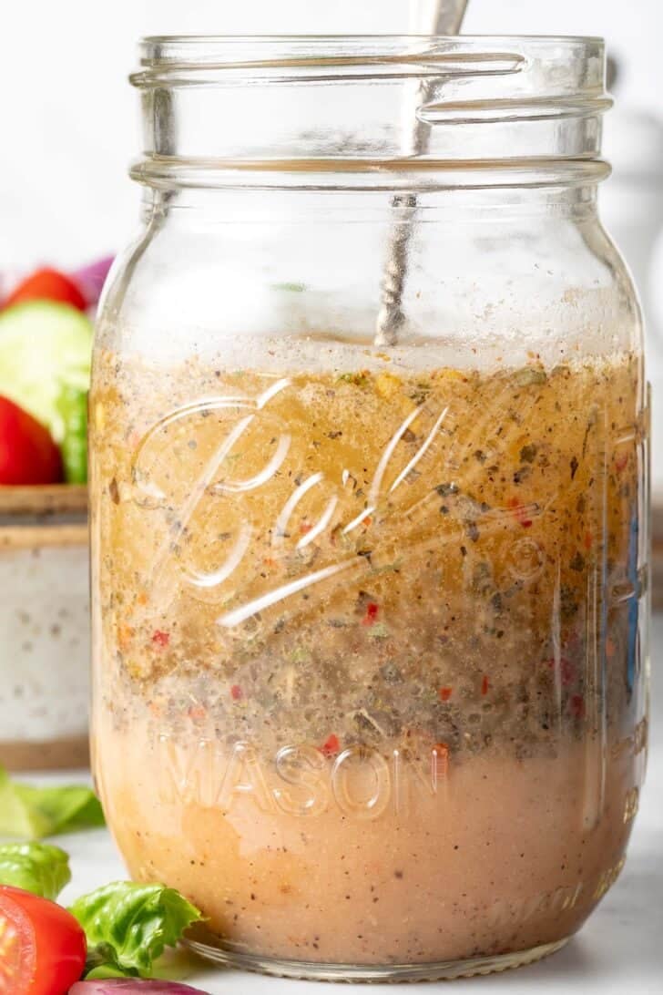 A clear mason jar filled with Zesty Italian Salad Dressing.
