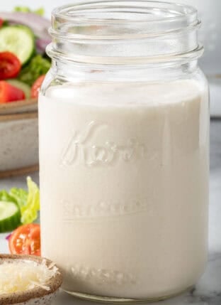 A clear mason jar filled with homemade Buttermilk Dressing.