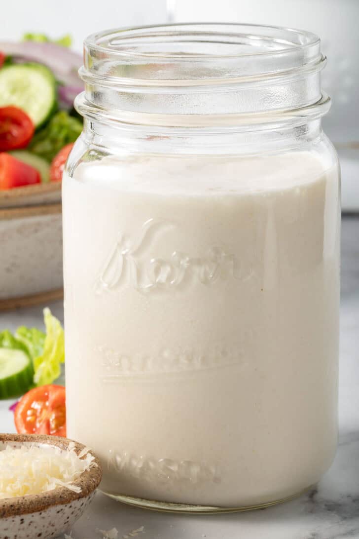 A clear mason jar filled with homemade buttermilk dressing.