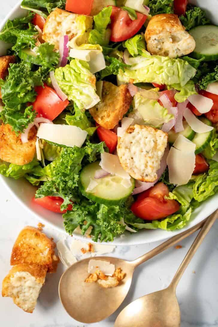 A white bowl filled with Easy Kale Salad with curly kale and gorgonzola croutons.