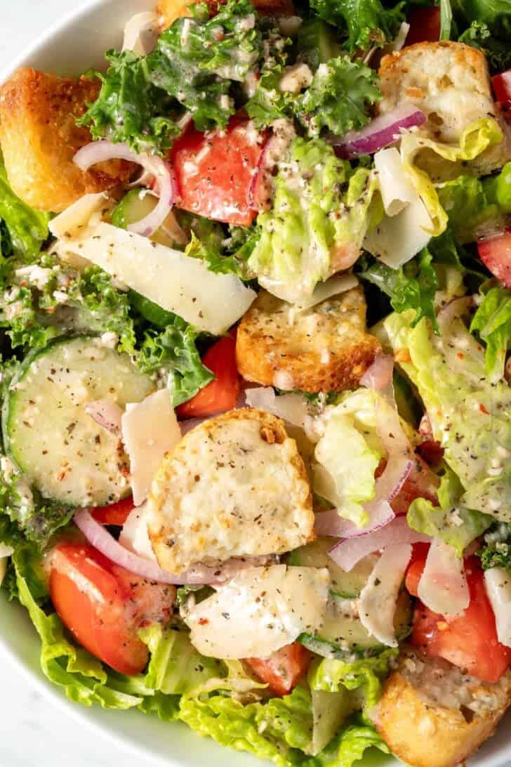 A white bowl filled with Simple Kale Salad with gorgonzola croutons.